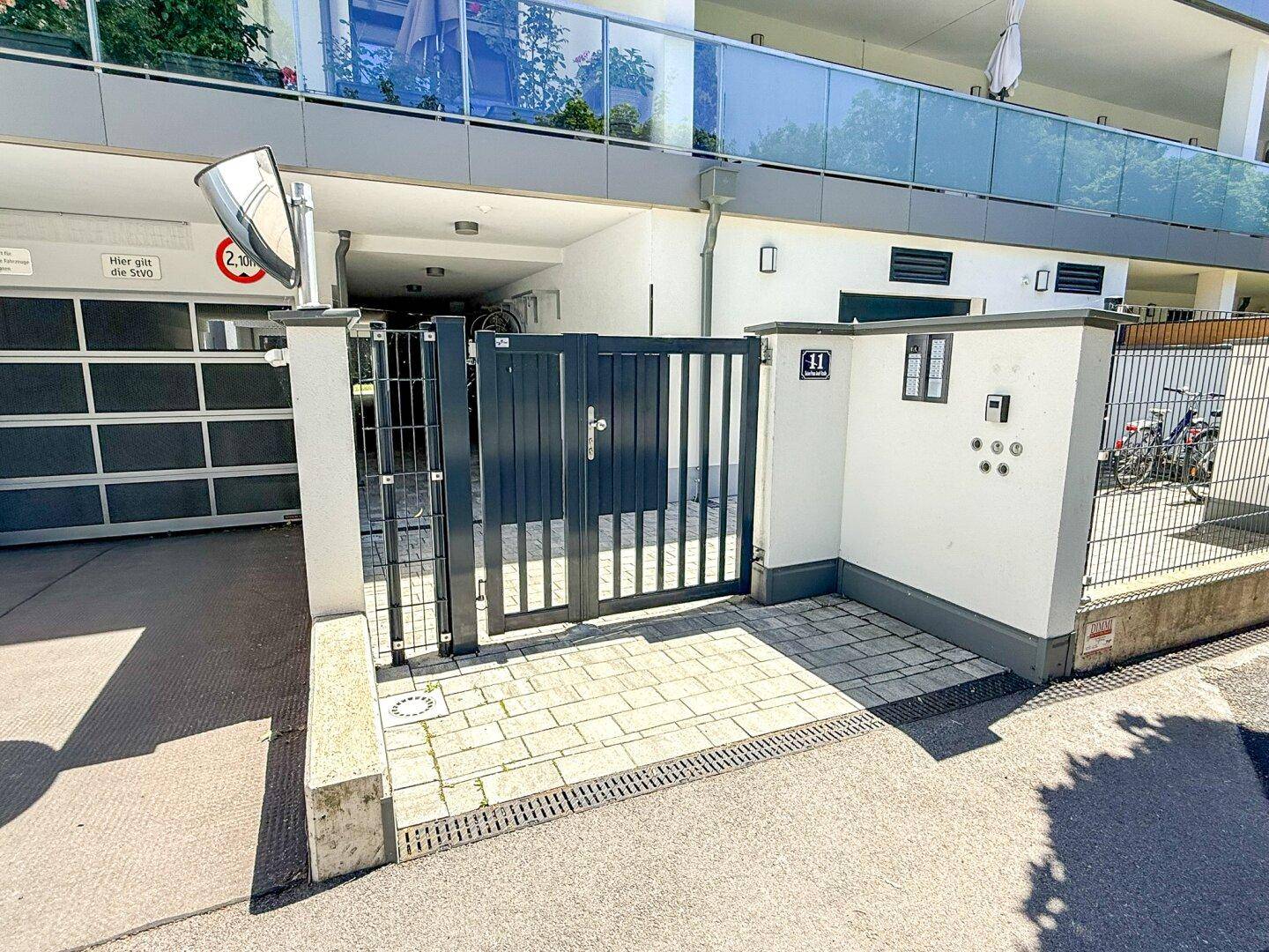 Eingangsbereich zur Tiefgarage mit Schiebetor und separatem Fußgängerzugang.