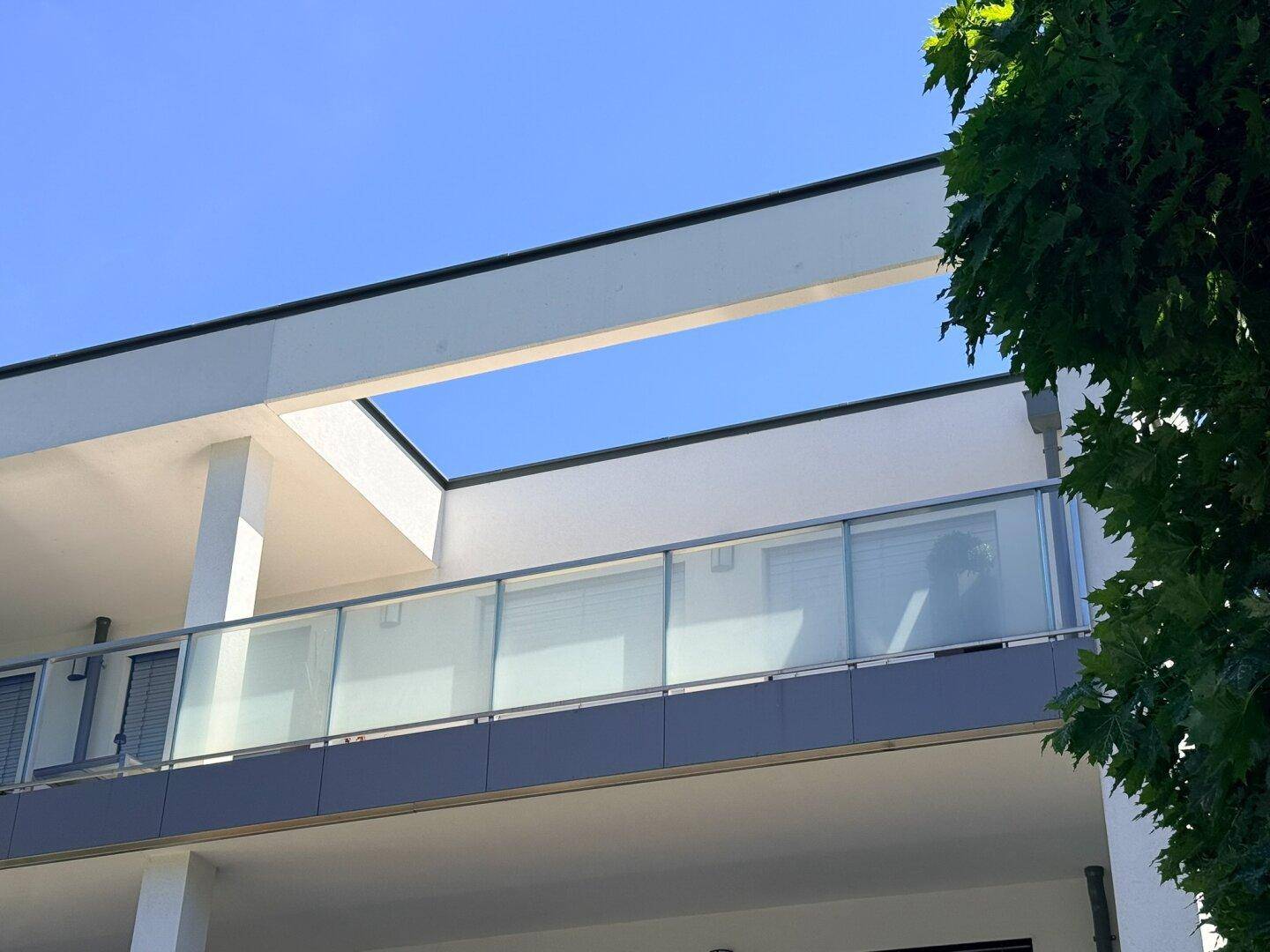 Detailansicht der modernen Fassade mit Glasbalkonen und klarem Himmel.