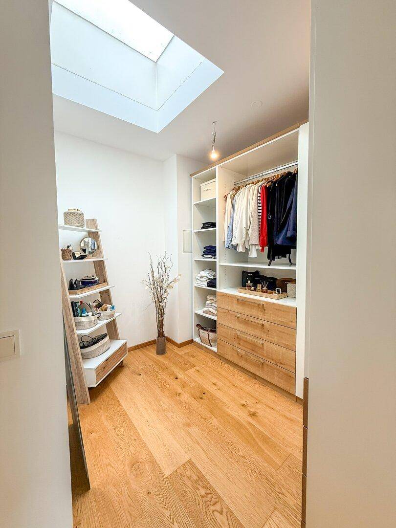 Geräumiger begehbarer Kleiderschrank mit Einbauschränken, Regalen und Oberlicht.