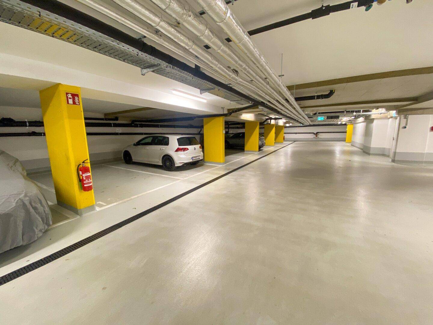 Geräumige Tiefgarage mit markierten Stellplätzen und hellen Säulen.