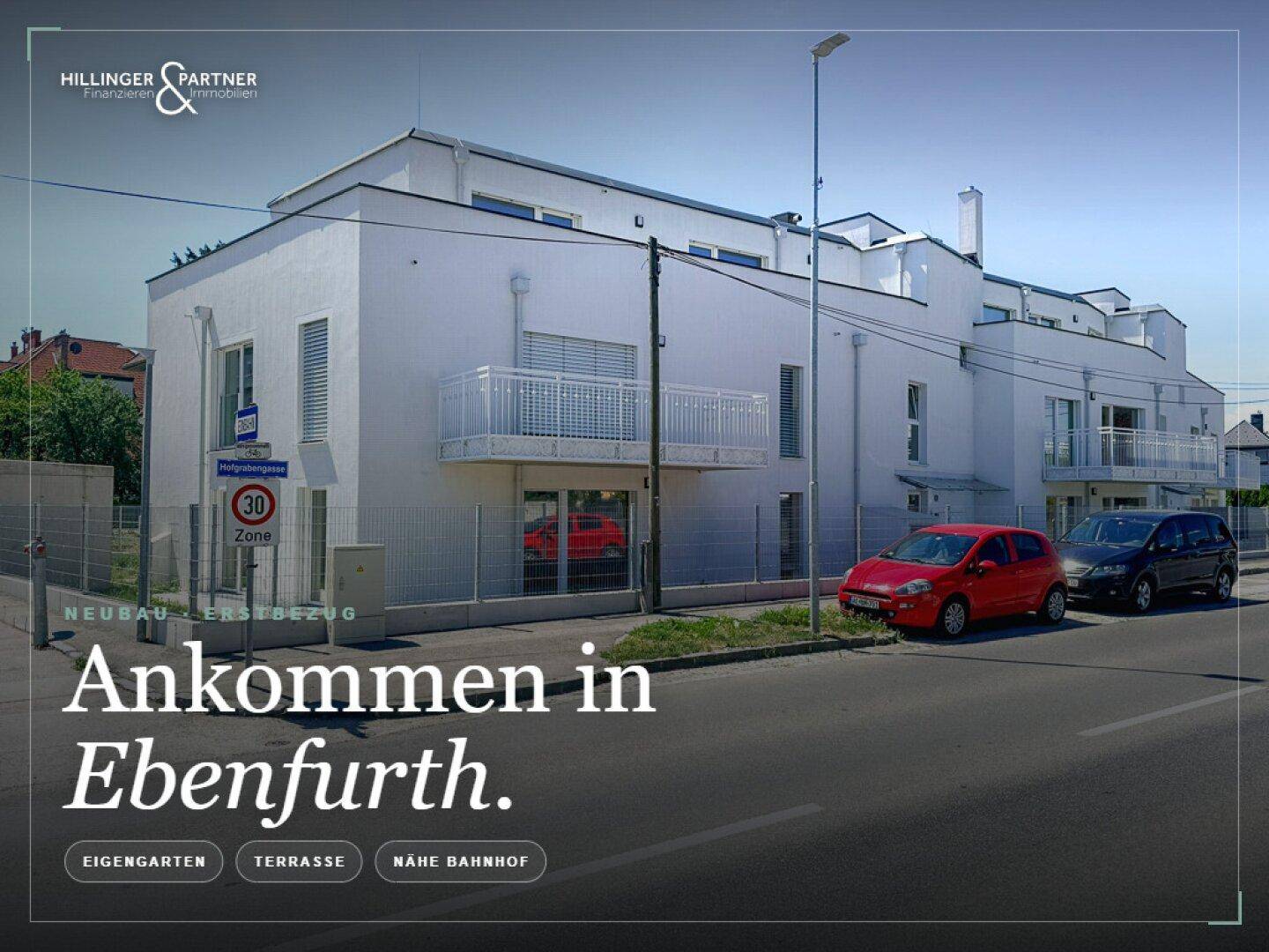 Ansicht der modernen weißen Gebäudefassade von der Straße mit geparkten Autos.