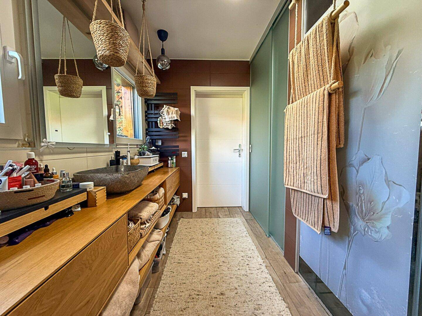 Modernes Badezimmer mit Holzwaschtisch, Steinsink und großer Dusche, ausgestattet mit Handtuchheizkörper.