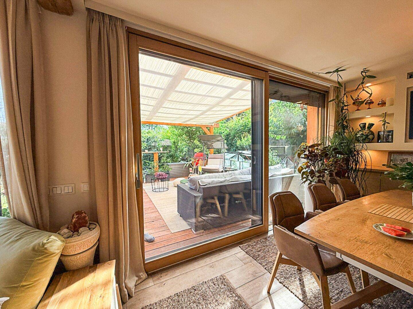 Blick vom Essbereich durch große Schiebetüren auf die überdachte Terrasse mit Gartenmöbeln.