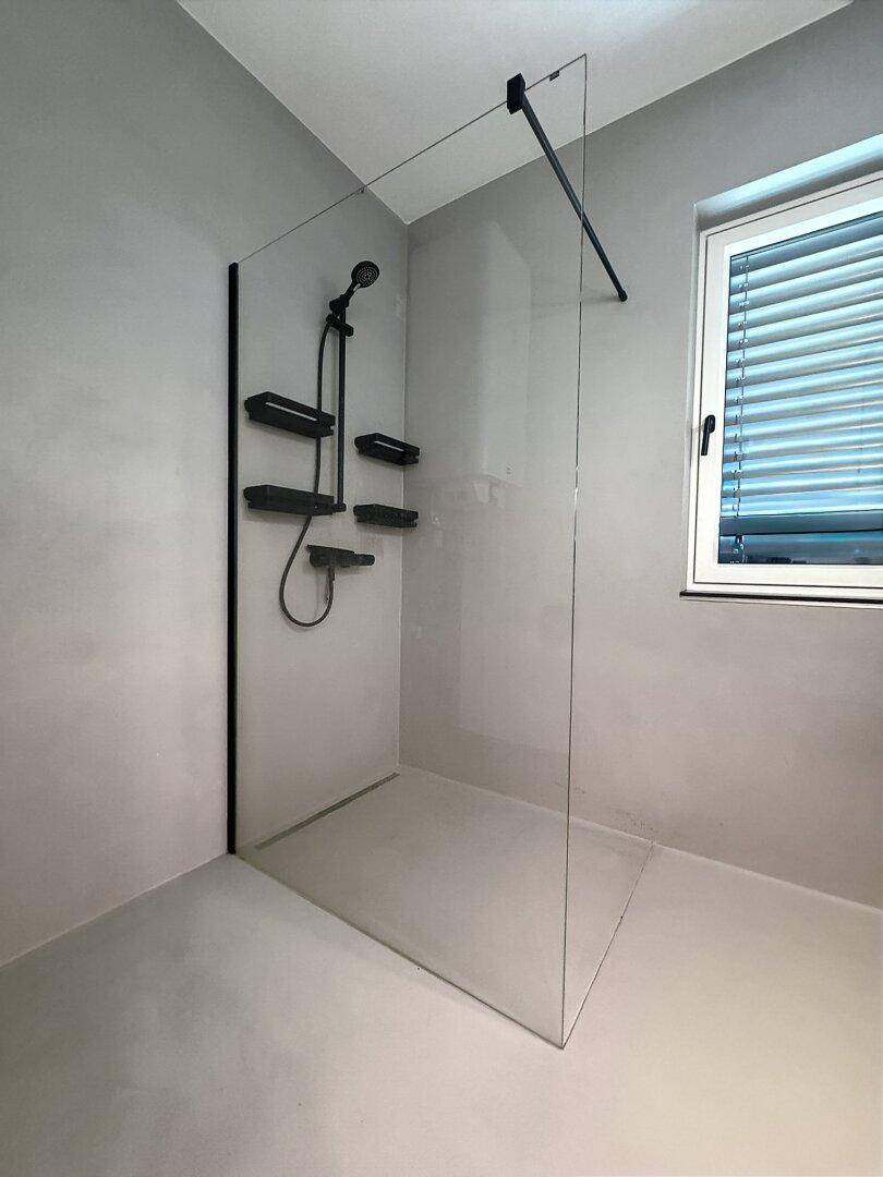 Geräumige, moderne begehbare Dusche mit Glasabtrennung und Fenster für natürliche Belüftung.
