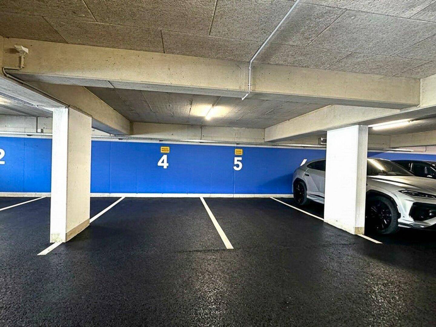 Tiefgarage mit markierten Stellplätzen und einem modernen Fahrzeug.