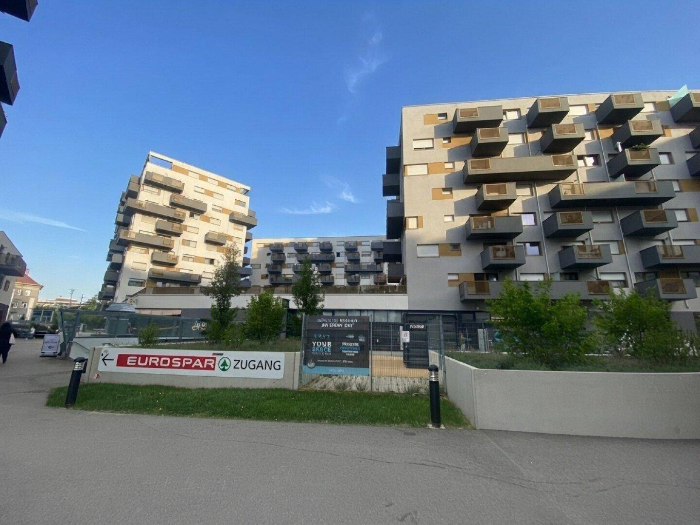Moderne Wohngebäude mit Geschäften im Erdgeschoss und Supermarktzugang.