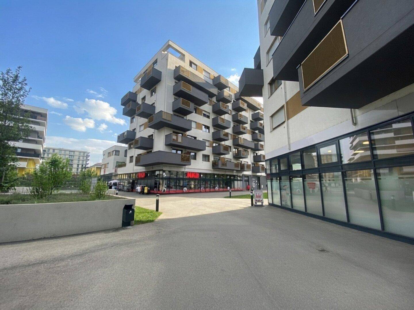 Moderne Wohnanlage mit markanter Architektur und Geschäften im Erdgeschoss.