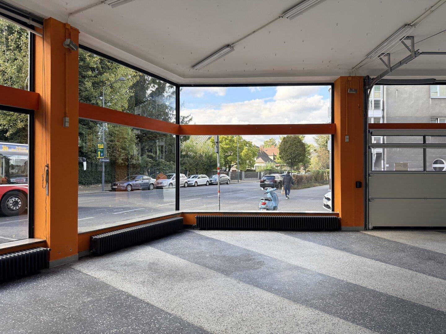 Heller Verkaufsraum mit großen Schaufenstern, die viel Tageslicht hereinlassen und Blick auf die Straße bieten.