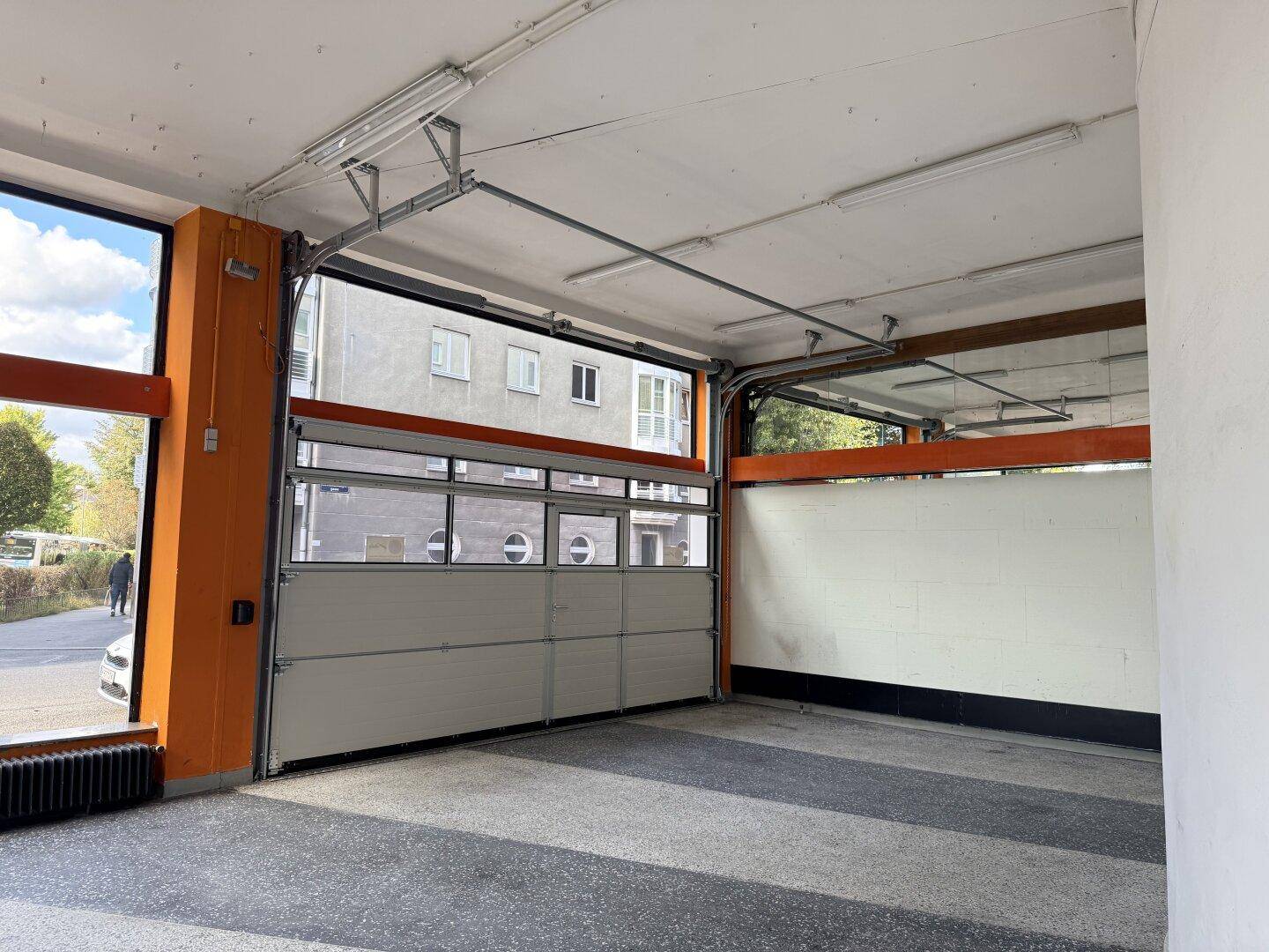 Innenansicht des Verkaufsraums mit geöffnetem Garagentor und Blick auf die Straße.
