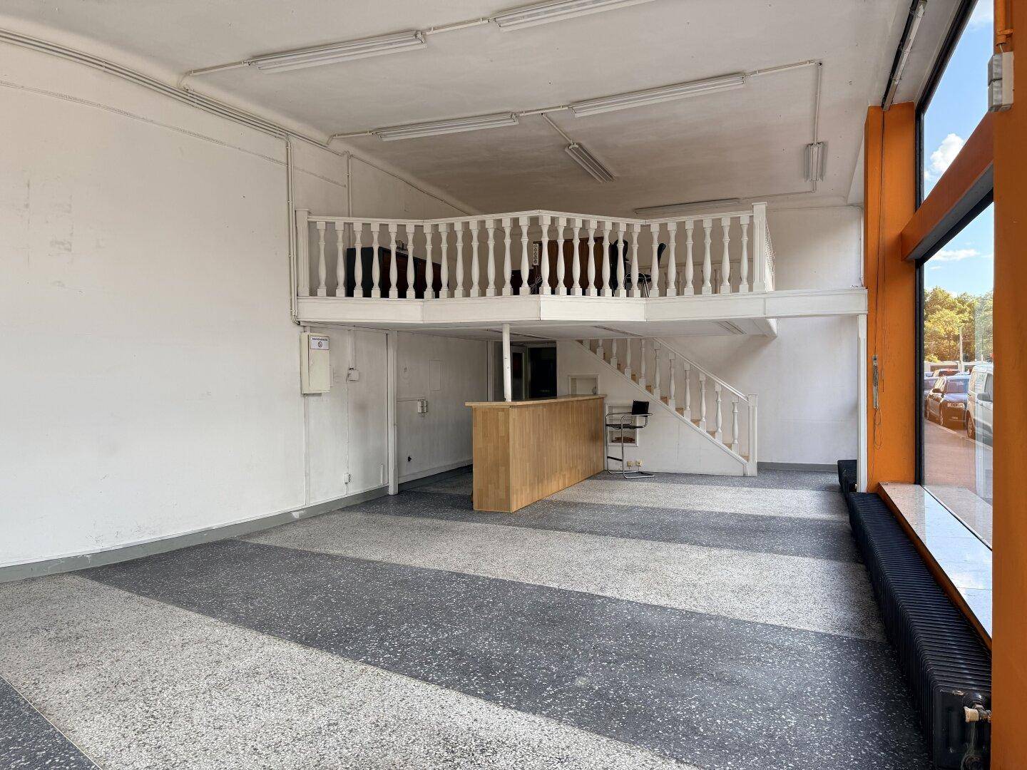 Geräumiger Verkaufsraum mit einer Holztheke und einer Empore mit Balustrade.