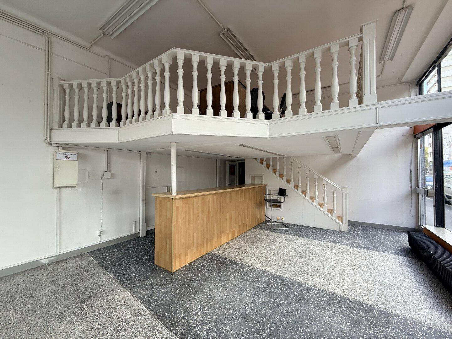 Geräumiger Verkaufsraum mit einer Holztheke und einer Empore mit weißer Balustrade.