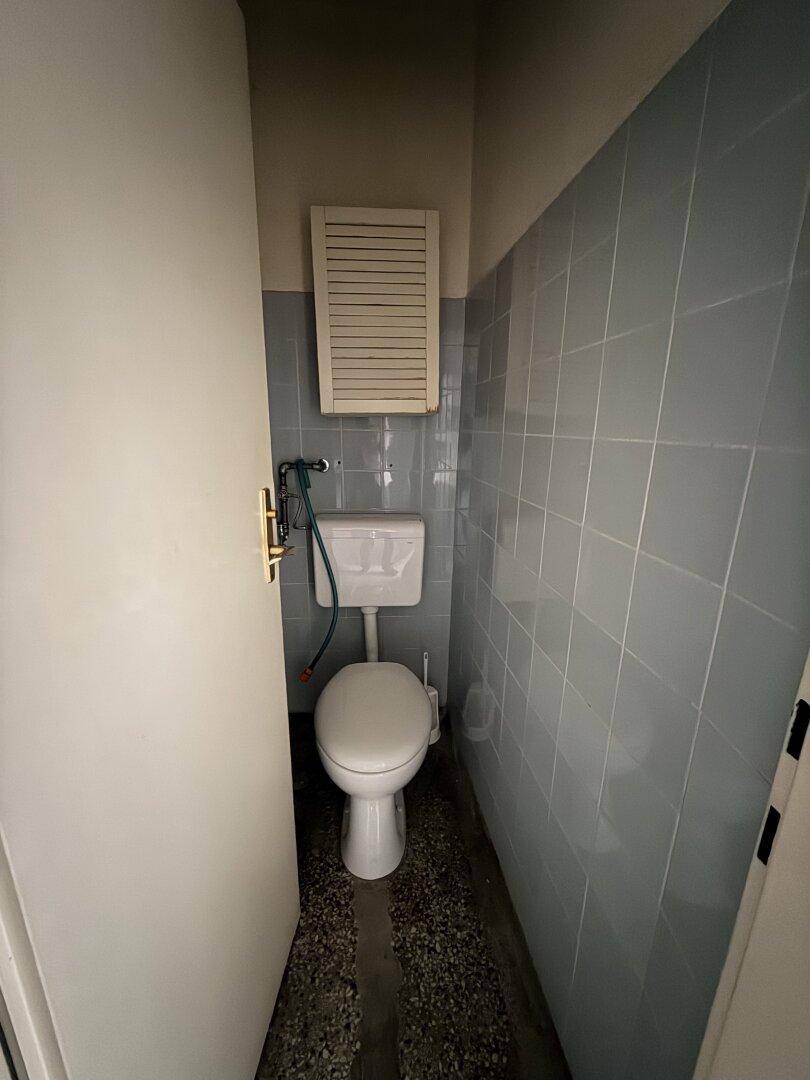 Toilettenraum mit WC und hellblauen Fliesen an den Wänden, funktional und sauber.