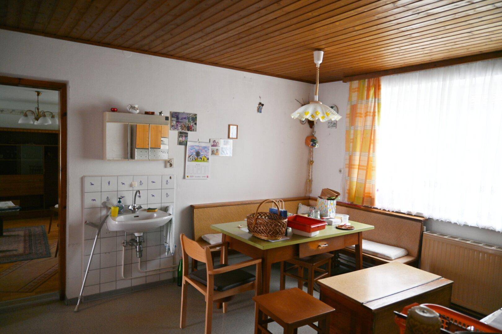 Einfache Wohnküche mit Essbereich, Spülbecken und Holzdecke.