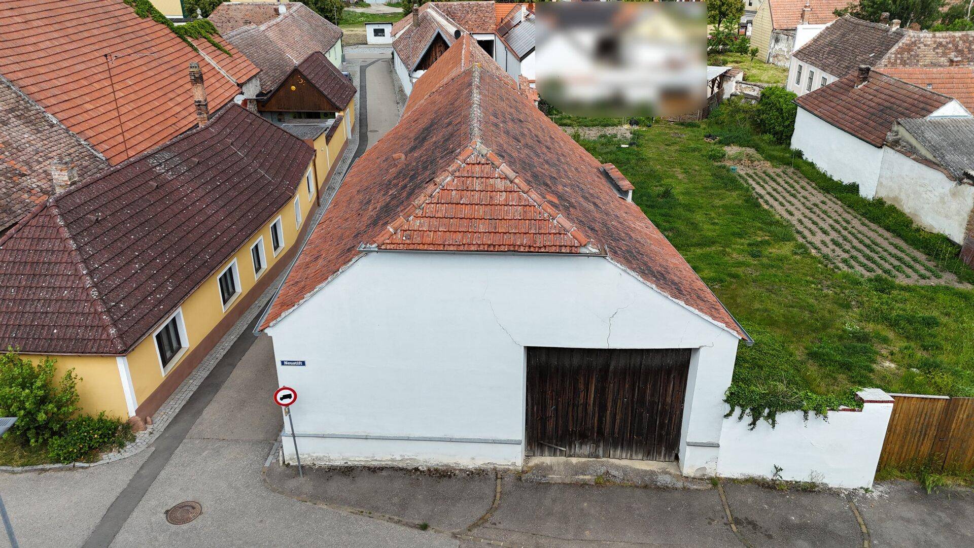 Luftaufnahme eines großen Scheunengebäudes mit Ziegeldach und angrenzendem Garten.