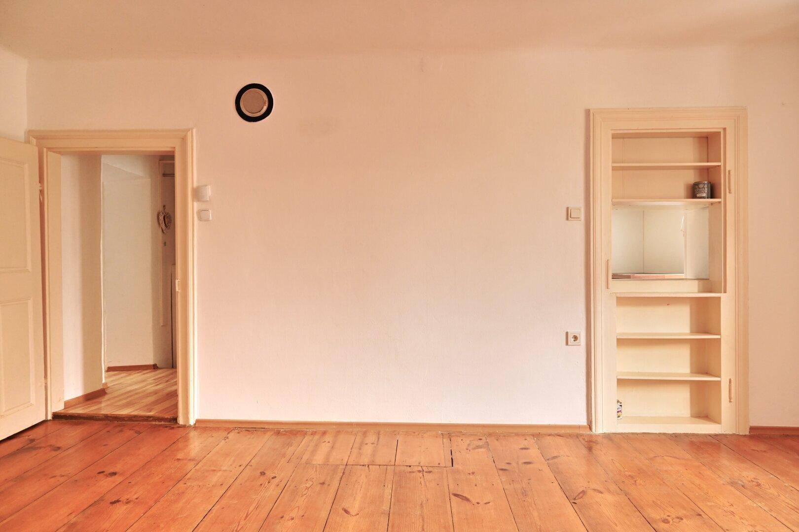 Wand mit integriertem Regal und einem Türrahmen, der zu einem anderen Bereich führt.