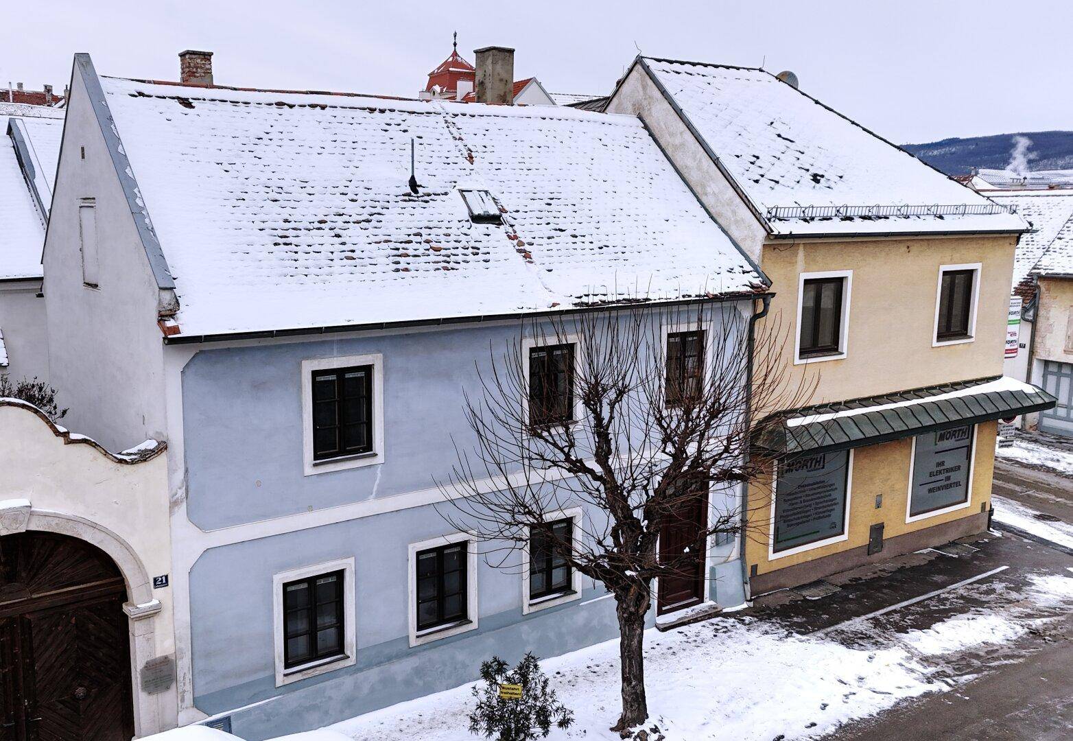 Winterliche Ansicht einer Straße mit schneebedeckten Dächern und historischen Gebäuden.