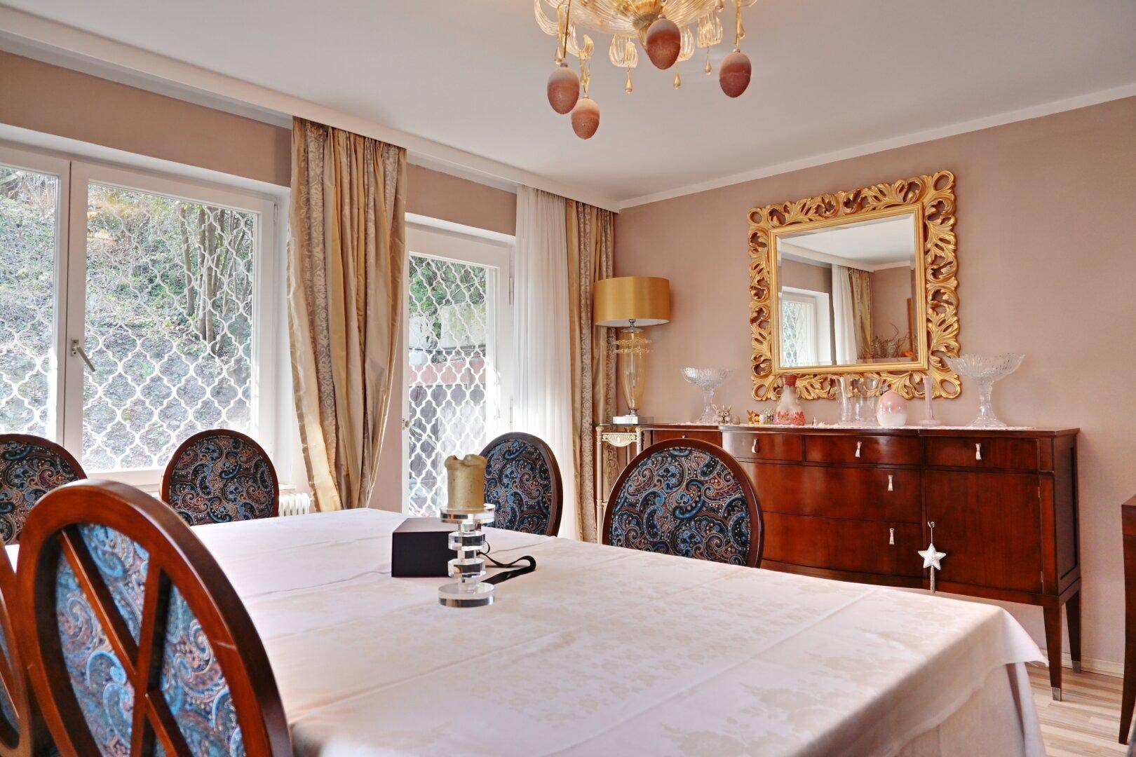 Elegantes Esszimmer mit antikem Sideboard, goldenem Spiegel und Kronleuchter.