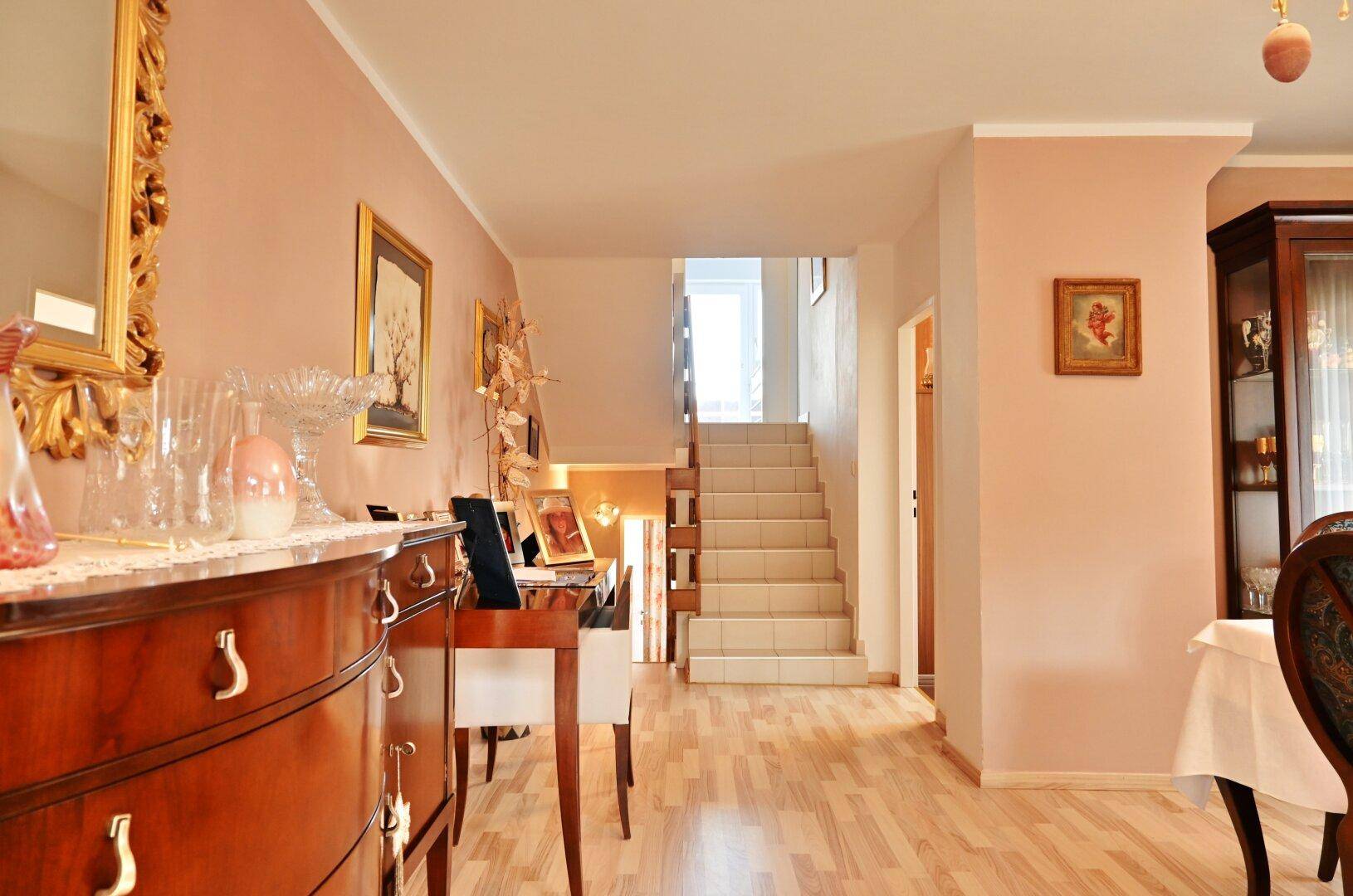 Heller Flur mit Holzparkettboden und Treppe zum Obergeschoss, klassisch eingerichtet.