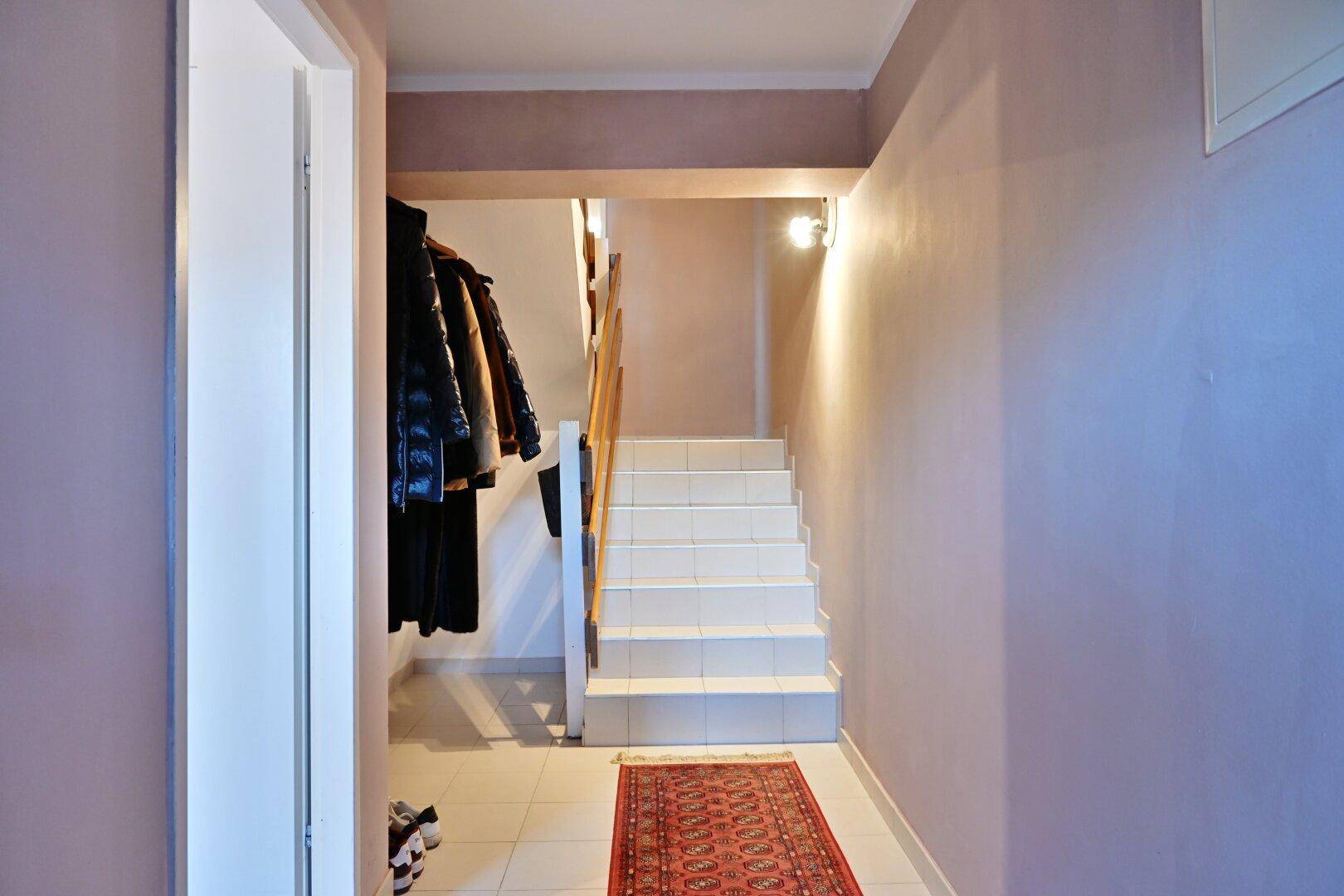 Eingangsbereich mit gefliester Treppe und Garderobe, in hellen Farbtönen gehalten.