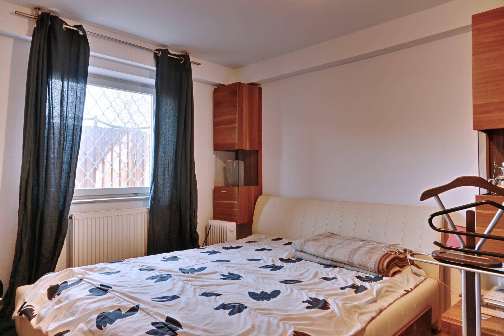 Schlafzimmer mit Doppelbett, Holzmöbeln und Fenster mit Blick ins Grüne.