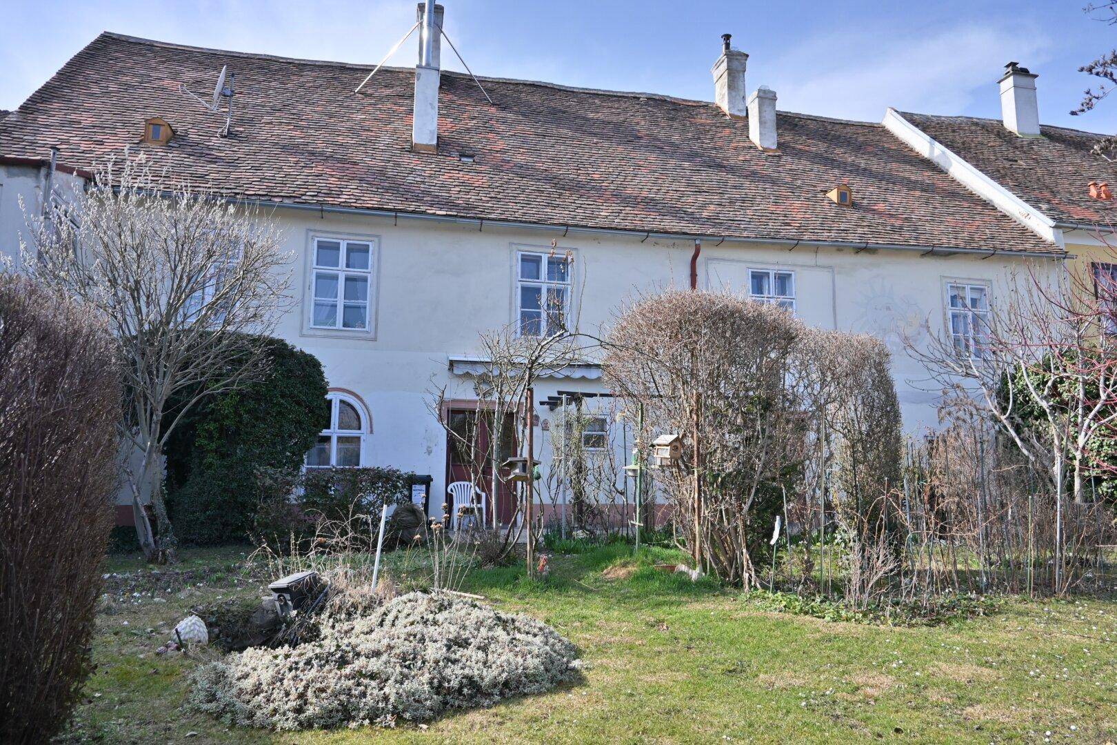 Rückseite des Hauses mit einem weitläufigen Garten und üppiger Bepflanzung.