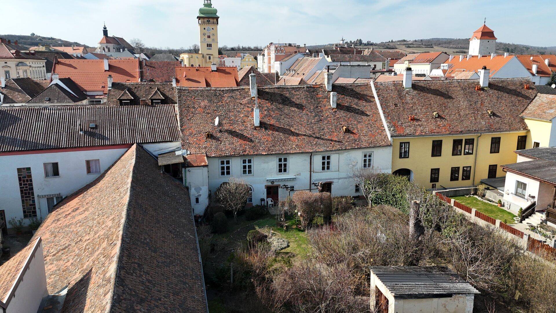 Luftaufnahme eines historischen Stadtteils mit traditionellen Dächern und einem großen Gartenbereich.