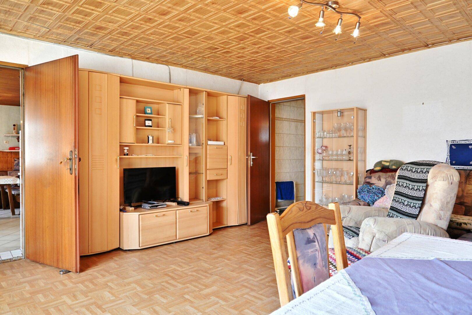 Gemütliches Wohnzimmer mit Holzdecke, Parkettboden und großem Wandschrank.