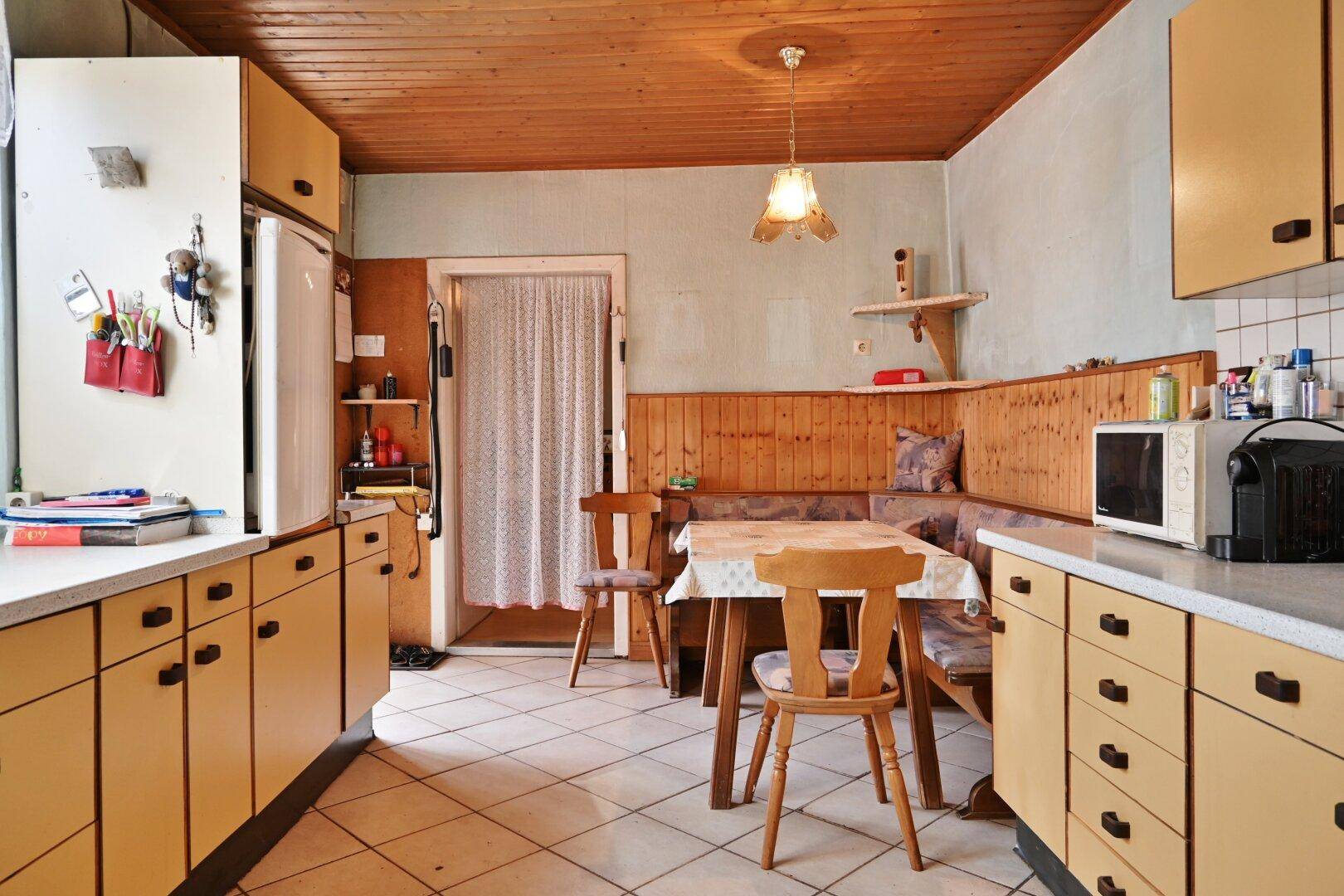 Geräumige Wohnküche mit Essecke, Holzdecke und traditionellen Küchenschränken.