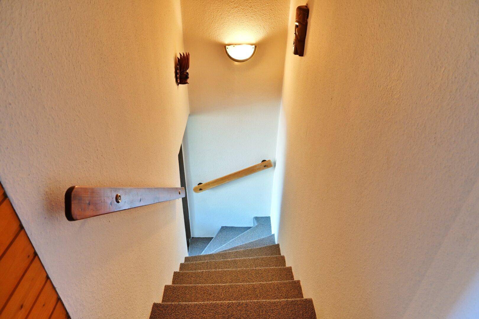 Treppenaufgang mit Teppichboden und Holzhandläufen, der die verschiedenen Etagen verbindet.