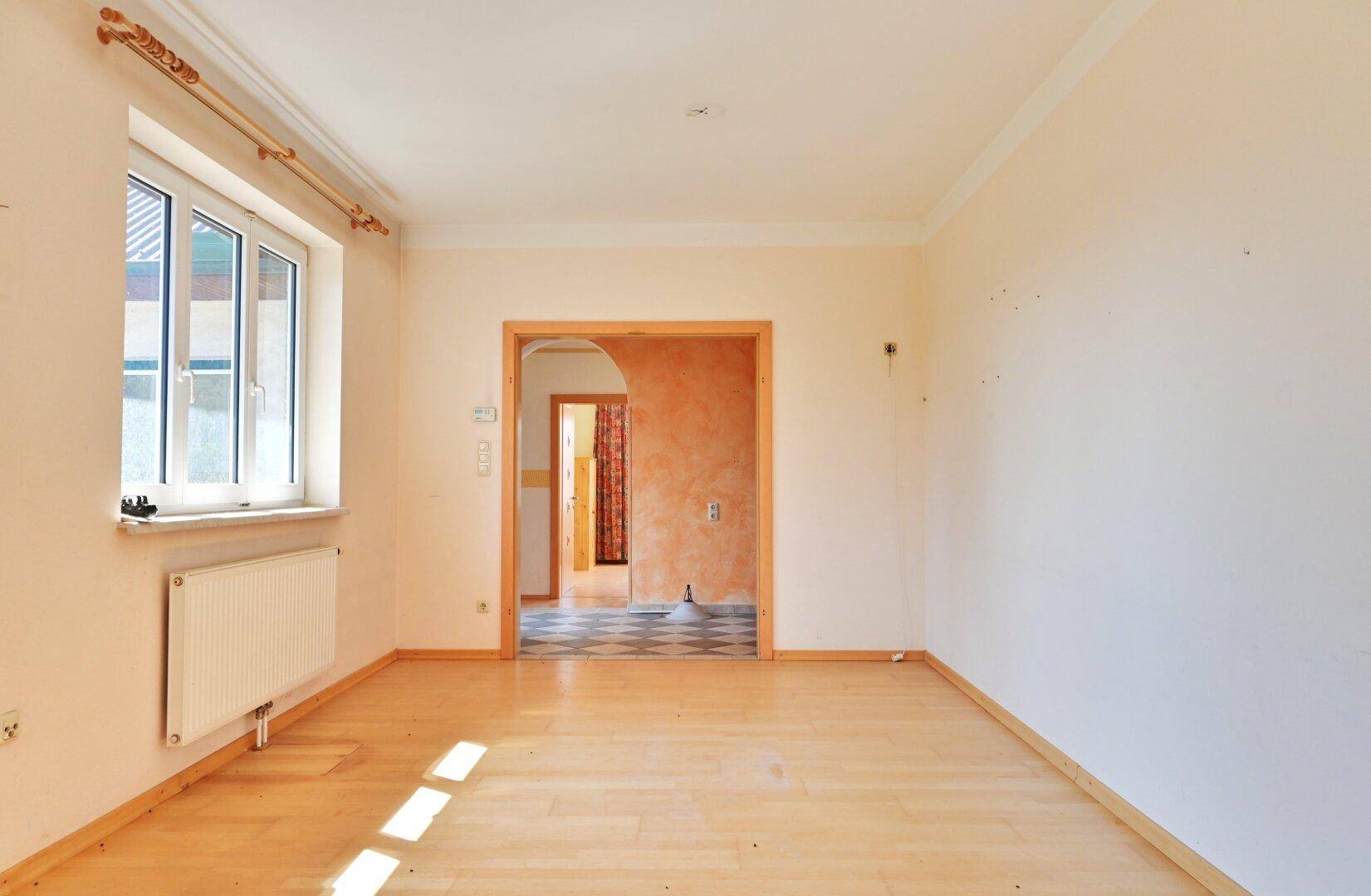 Heller, leerer Raum mit Parkettboden und Zugang zu einem weiteren Zimmer.