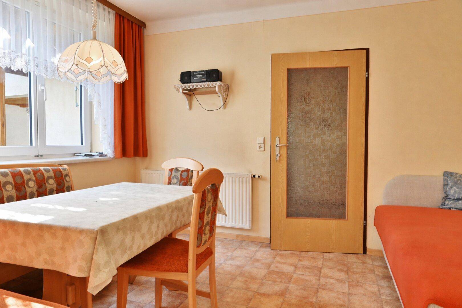 Heller Essbereich mit großem Fenster, Esstisch und traditioneller Deckenleuchte.