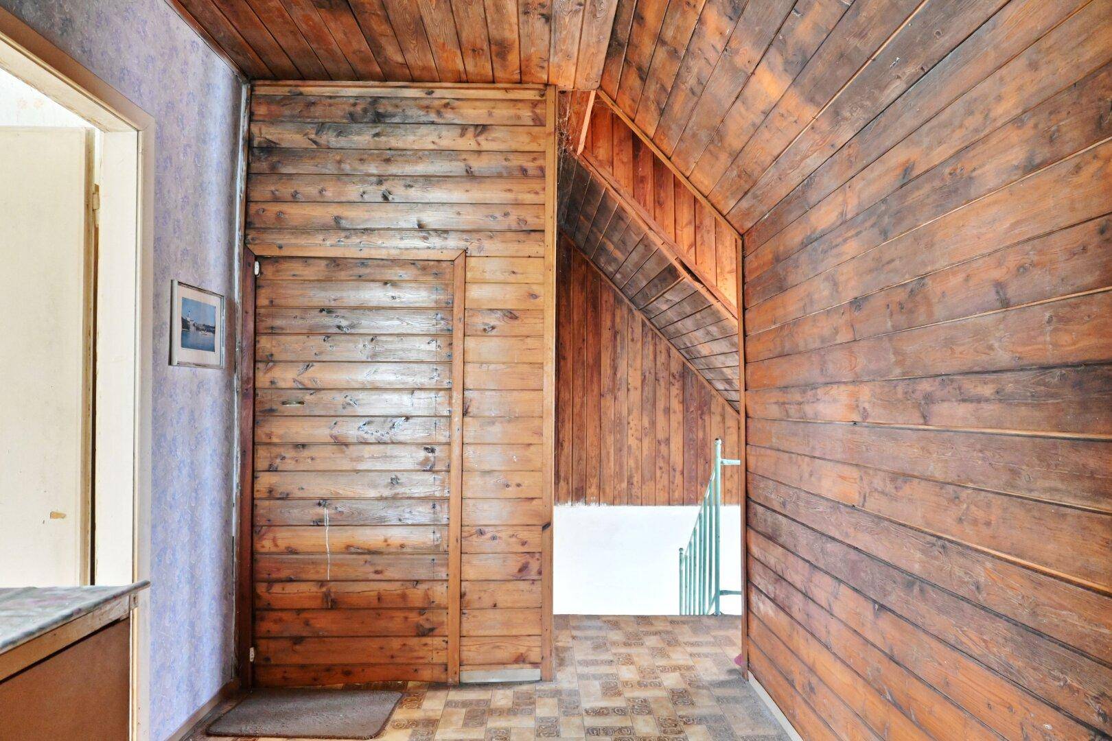 Flur mit Holzvertäfelung an den Wänden und einer Treppe, die in ein oberes Stockwerk führt.