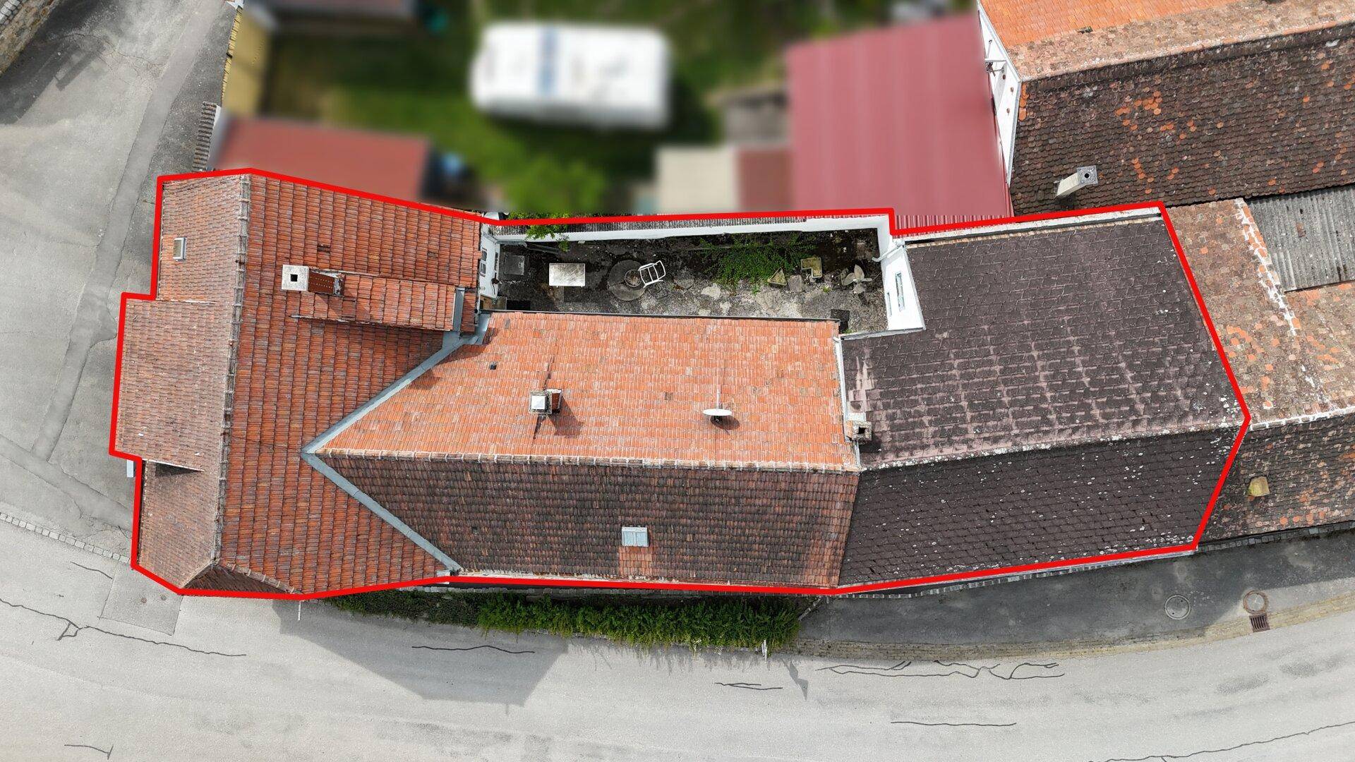 Luftaufnahme des Anwesens mit rot markierter Grundstücksgrenze und Ziegeldächern.