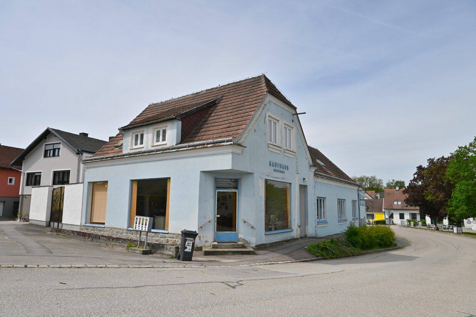 Ansicht des Gebäudes von der Straße aus, mit hellblauer Fassade und traditionellem Ziegeldach.