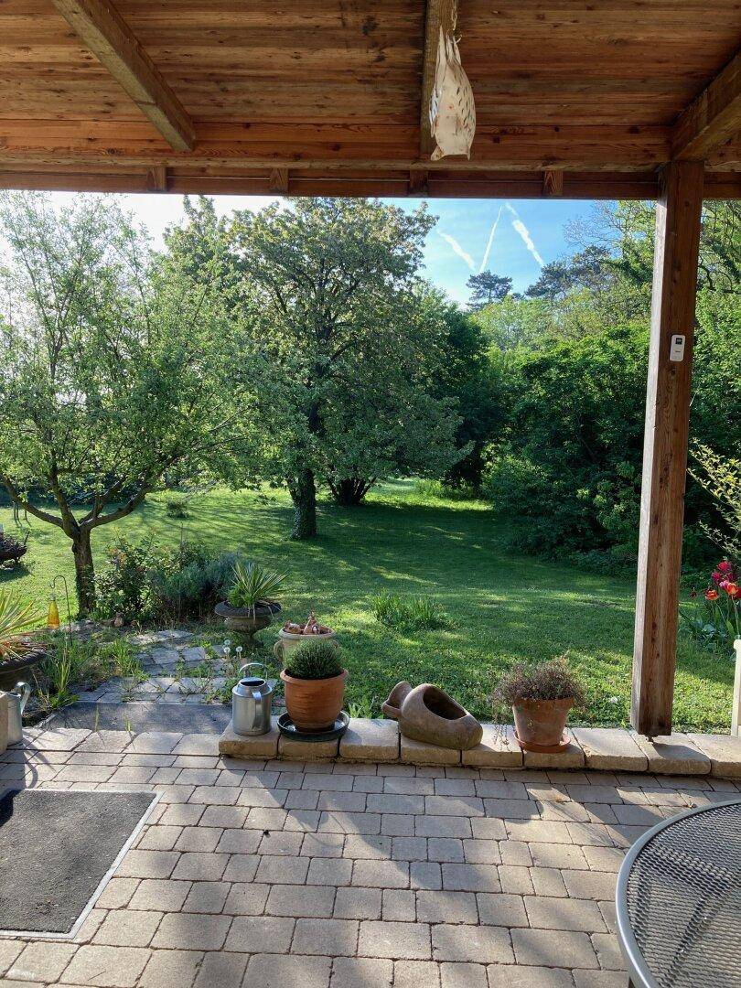 Überdachte Terrasse mit Blick auf den weitläufigen Garten und die grüne Umgebung.