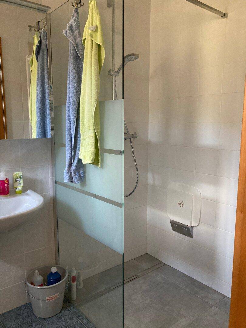 Modernes Badezimmer mit ebenerdiger Dusche und hellen Wandfliesen.