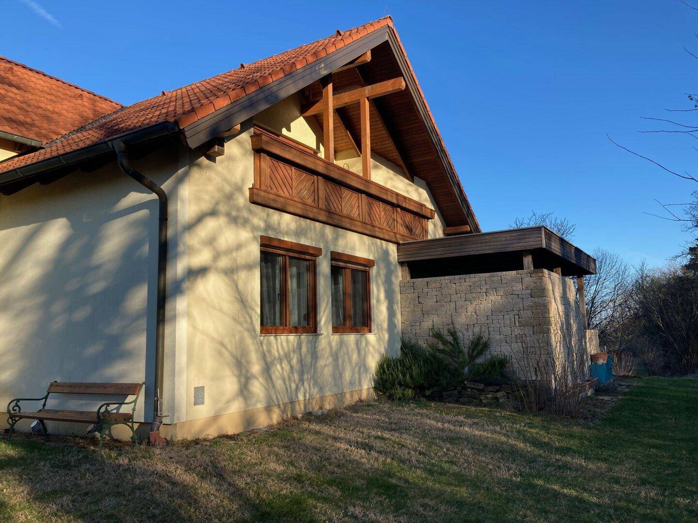Seitenansicht des Hauses mit Natursteinmauer und traditionellem Ziegeldach.