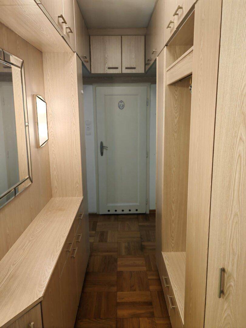 Heller Flur mit praktischen Einbauschränken aus hellem Holz und einem Spiegel.