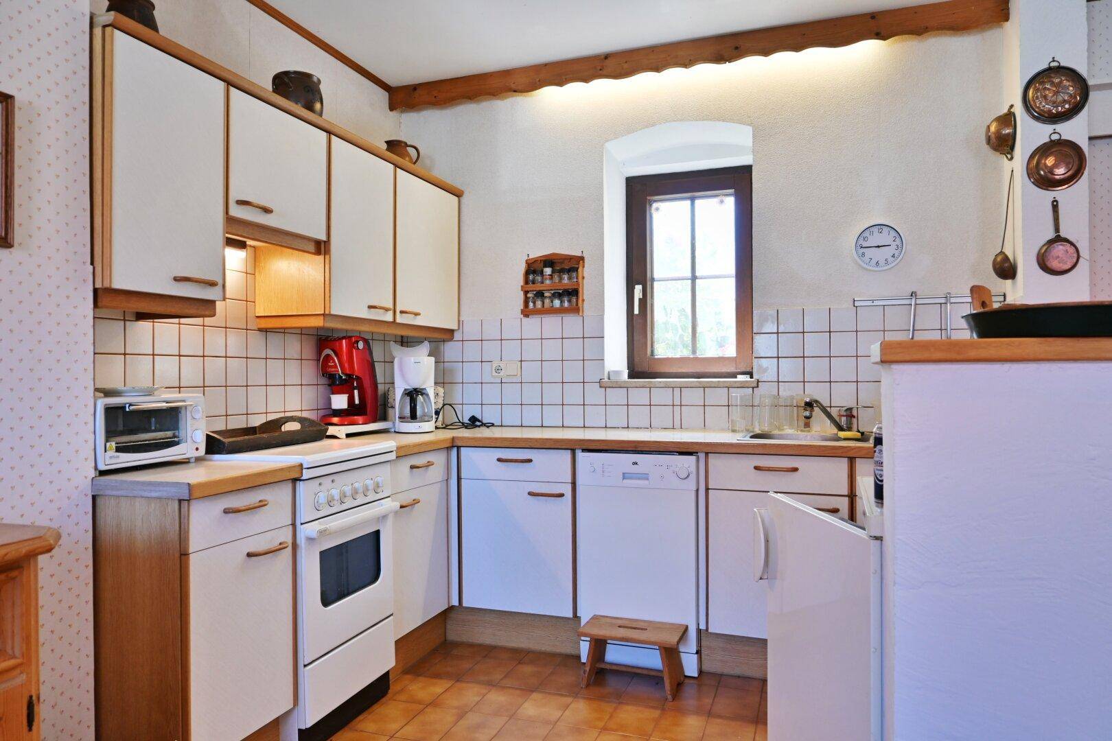 Funktionale Küche im Landhausstil mit weißen Schränken, Fliesenboden und Holzarbeitsplatten.