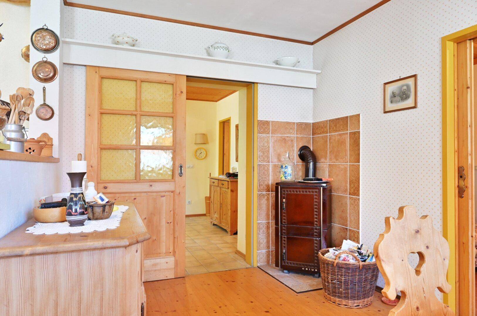 Eingangsbereich mit Holzfußboden, Kachelofen und Durchgang zu weiteren Räumen im Landhausstil.