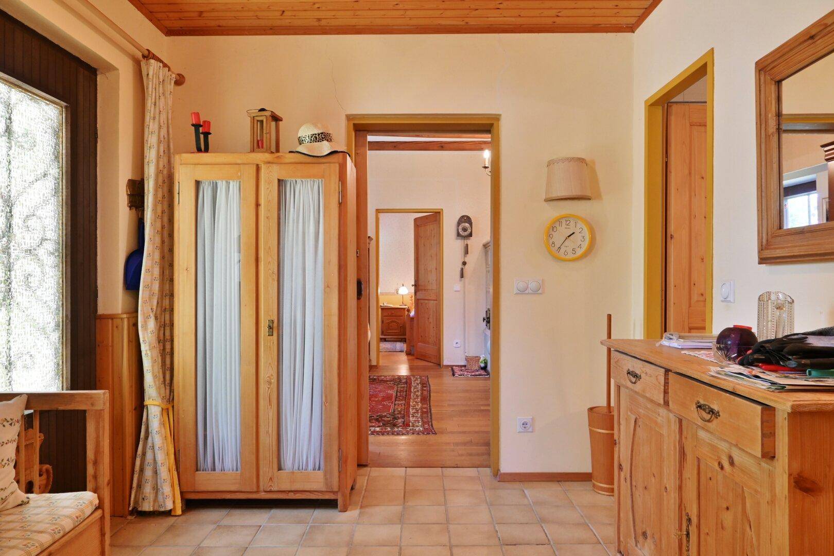 Heller Flur mit Fliesenboden, Holzdecke und Blick in angrenzende Zimmer des Landhauses.