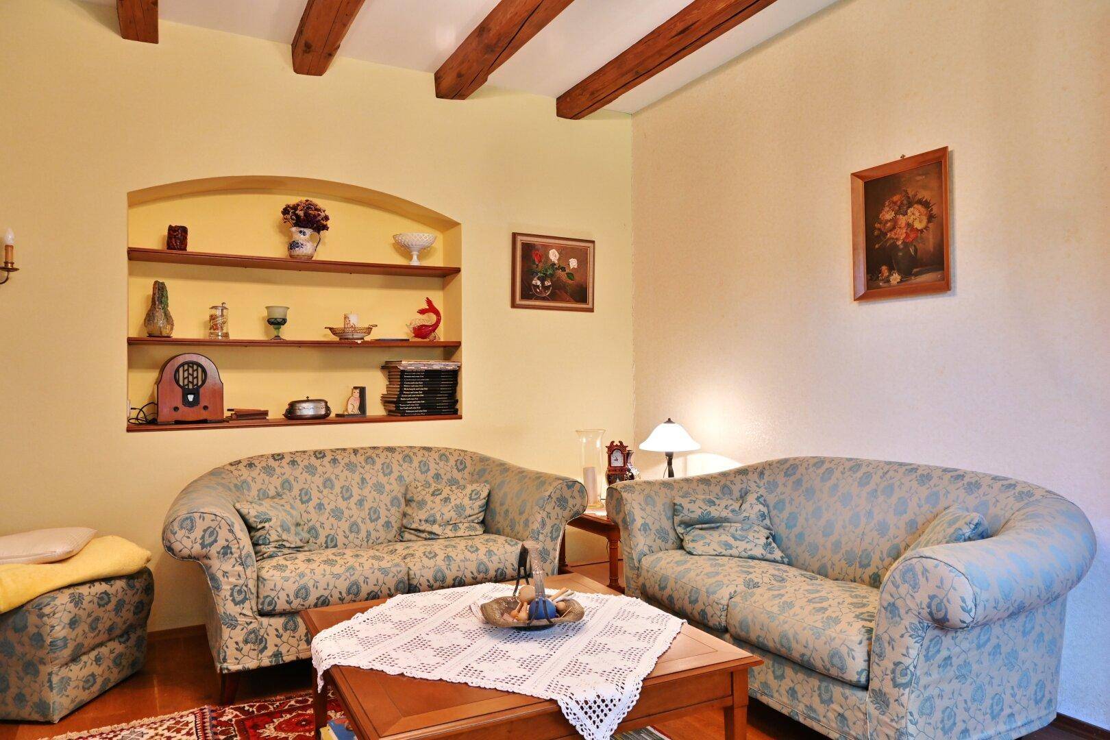 Wohnzimmer mit bequemen Sofas, Holzbalkendecke und traditioneller Einrichtung im Landhausstil.