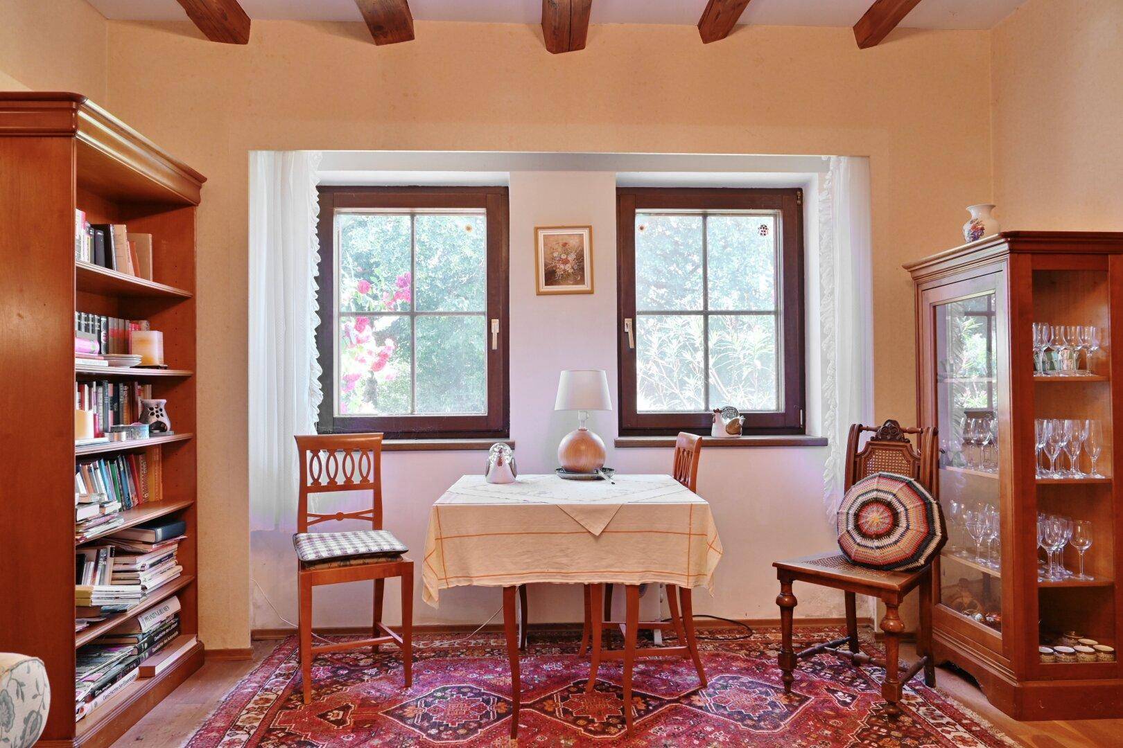 Kleiner Essbereich oder Leseecke im Wohnzimmer mit Holzbücherregal und Blick ins Grüne.