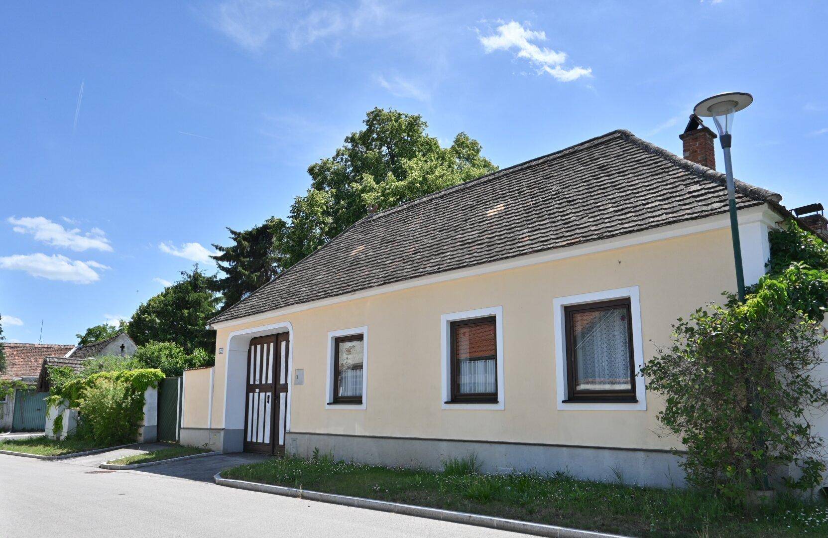 Charmantes Landhaus mit gelber Fassade, braunen Fenstern und traditioneller Architektur.