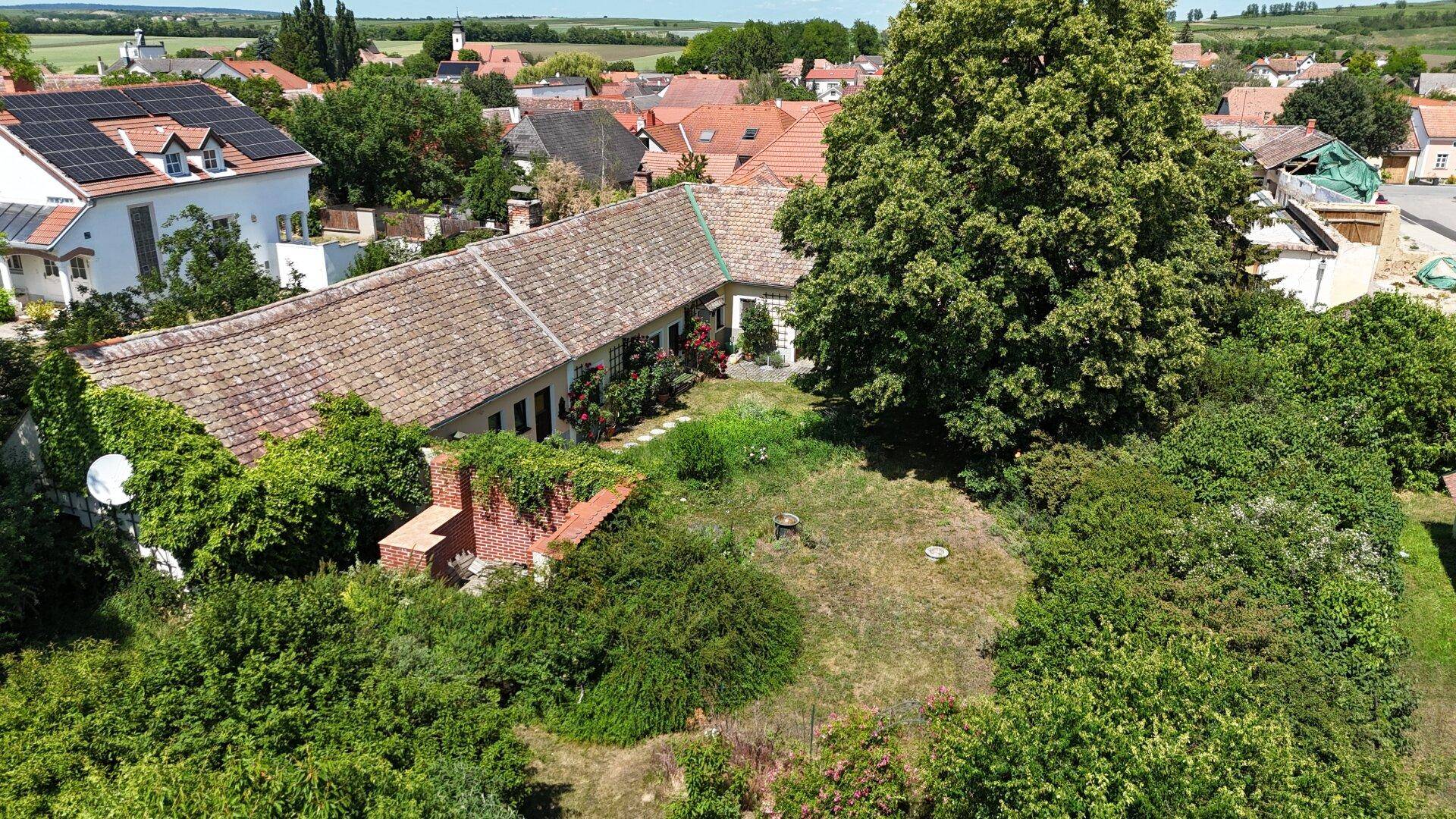 Weitläufiger Gartenbereich eines Landhauses mit altem Baumbestand und Blick auf die ländliche Umgebung.