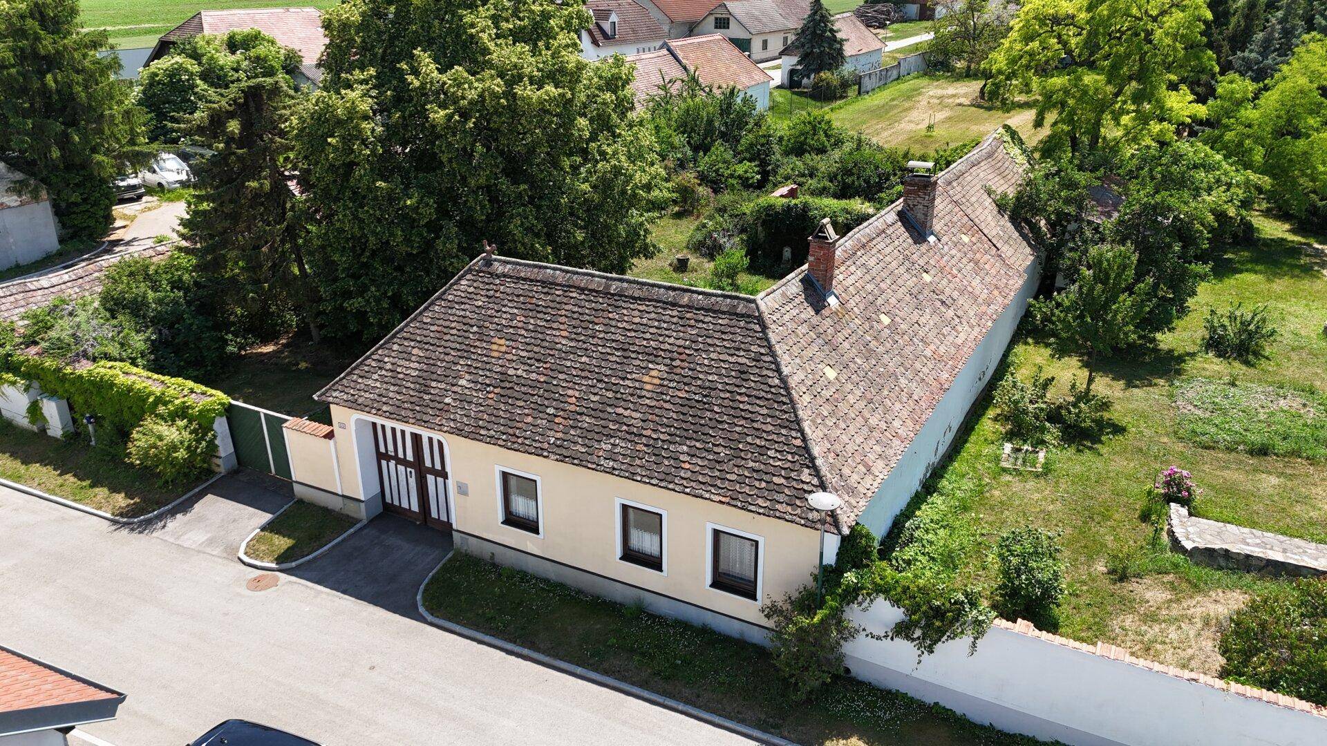 Luftaufnahme eines traditionellen Landhauses mit Ziegeldach und umgebender ländlicher Bebauung.