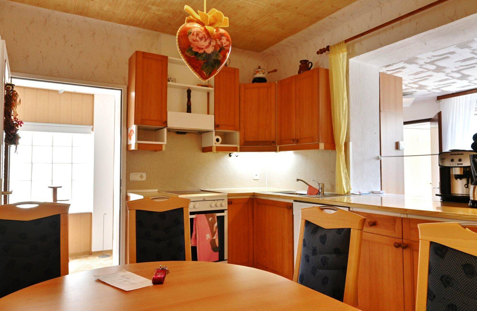 Küche mit Holzeinbauten, Esstisch und Blick in den angrenzenden Wohnbereich.
