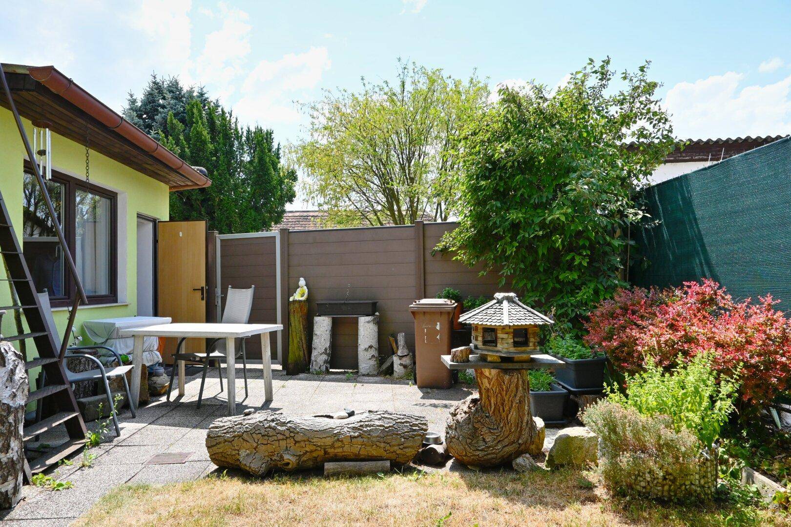 Garten mit Terrasse, Sitzgelegenheiten, Vogelhaus und Zugang zum Haus.