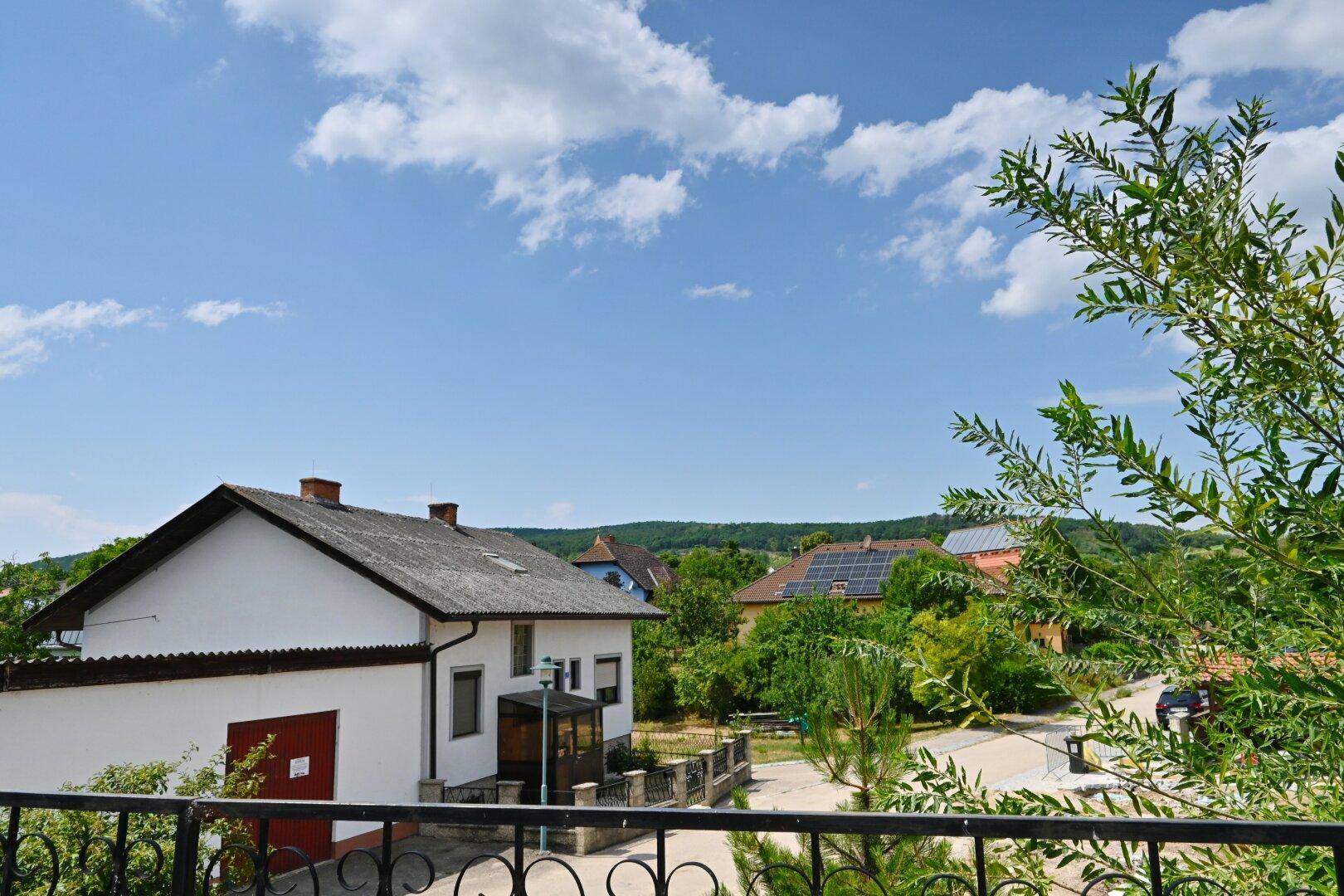 Balkon mit weitem Blick über die Dächer der Nachbarschaft und grüne Hügel.