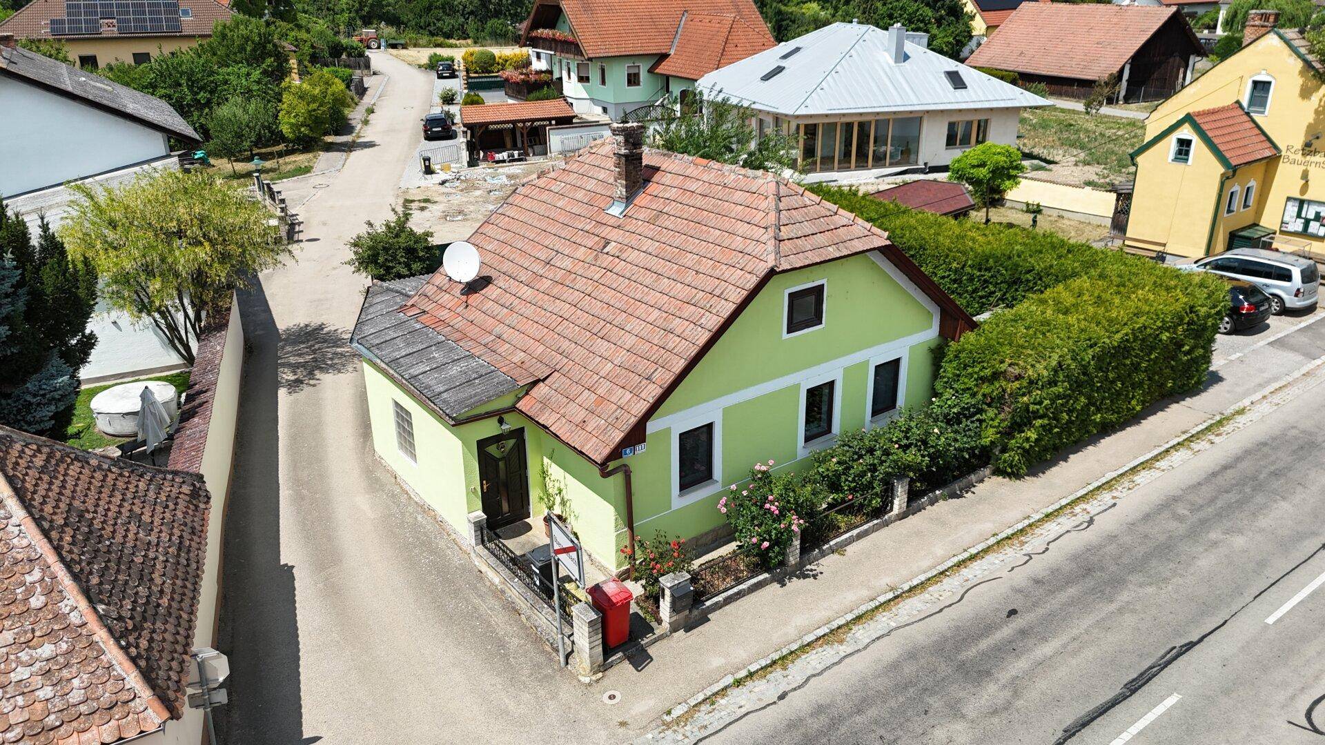 Luftaufnahme des grünen Hauses mit Satteldach, umgeben von Gärten und Nachbargebäuden.